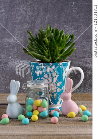 Cup with succulent, jar with Easter candies and bunny figurines. Cup with succulent, jar with Easter candies and bunny figurines. 121531713