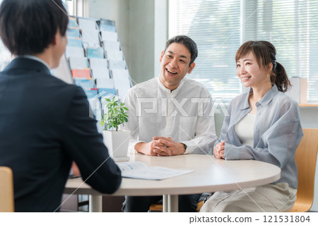 A couple listening to a conversation in a showroom/business negotiation space and a businessman serving them 121531804