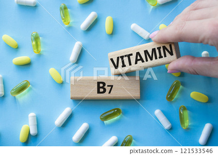 Vitamin B7 symbol. Concept word Vitamin B7 on wooden blocks. Beautiful blue background with pills. Doctor Hand. Medicine and Vitamin B7 concept. Copy space 121533546