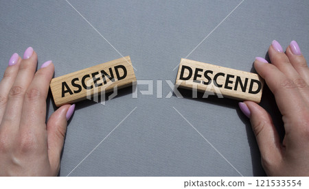 Ascend or Descend symbol. Concept word Ascend or Descend on wooden blocks. Businessman hand. Beautiful grey background. Business and Ascend or Descend concept. Copy space Ascend or Descend symbol. Concept word Ascend or Descend on wooden blocks. Businessman hand. Beautiful grey background. Business and Ascend or Descend concept. Copy space 121533554