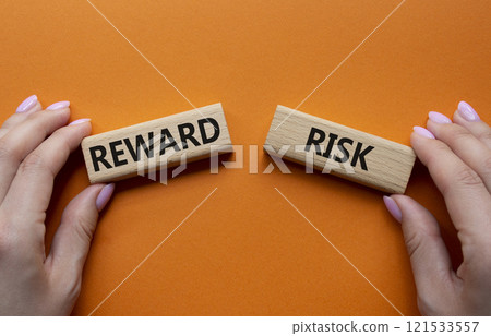 Risk or Reward symbol. Concept word Risk or Reward on wooden blocks. Businessman hand. Beautiful orange background. Business and Risk or Reward concept. Copy space 121533557