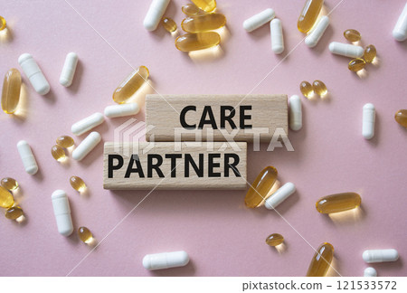 Care Partner symbol. Concept word. Care Partner on wooden blocks. Beautiful pink background with pills. Medicine and Care Partner concept. Copy space 121533572