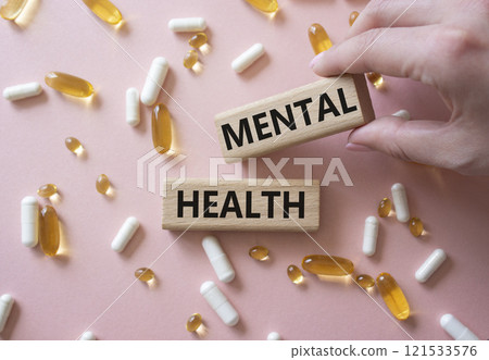 Mental Health symbol. Concept word Mental Health on wooden blocks. Doctor Hand. Beautiful pink background with pills. Medicine and Mental Health concept. Copy space Mental Health symbol. Concept word Mental Health on wooden blocks. Doctor Hand. Beautiful pink background with pills. Medicine and Mental Health concept. Copy space 121533576