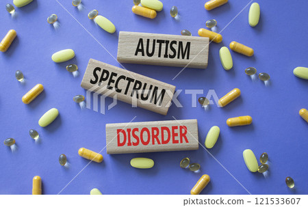 Autism Spectrum Disorder symbol. Concept word Autism Spectrum Disorder on wooden blocks. Beautiful purple background with pills. Medicine and Autism Spectrum Disorder concept. Copy space 121533607