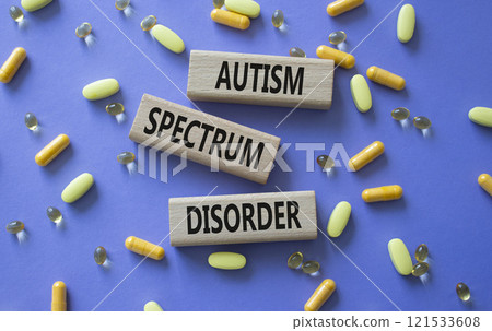 Autism Spectrum Disorder symbol. Concept word Autism Spectrum Disorder on wooden blocks. Beautiful purple background with pills. Medicine and Autism Spectrum Disorder concept. Copy space 121533608
