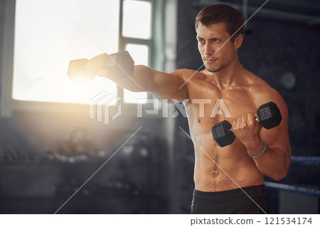 Fitness Enthusiast Engaging in a Dumbbell Exercise Routine in the Gym Environment Fitness Enthusiast Engaging in a Dumbbell Exercise Routine in the Gym Environment 121534174