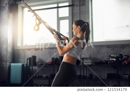 Fitness enthusiast using TRX training in a gym to enhance performance, strength, and wellbeing 121534179