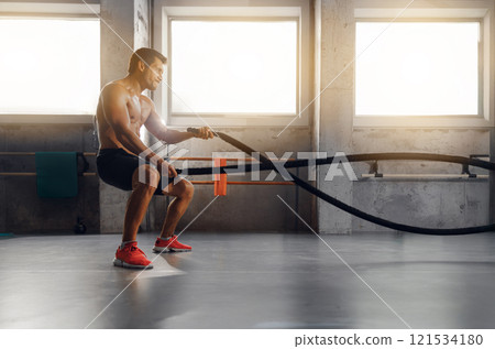 Using battle ropes in a modern gym for athletes and fitness enthusiasts during intense workouts 121534180
