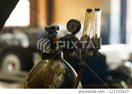 Pressure gauge and gas cylinder in a workshop setting showcasing craftsmanship Pressure gauge and gas cylinder in a workshop setting showcasing craftsmanship 121535627