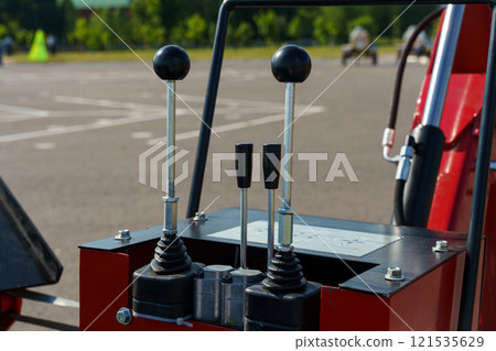 Control levers of a machinery vehicle parked on an empty lot during bright day Control levers of a machinery vehicle parked on an empty lot during bright day 121535629