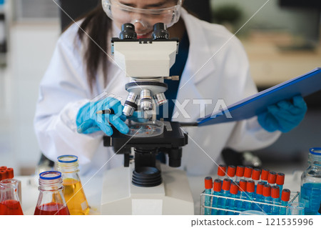 Chemist scientist holding test tube and tablet conducting experiment in laboratory with equipment, science concept. 121535996