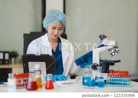 Doctor writes a note and uses a calculator to calculate expenses. 121535999