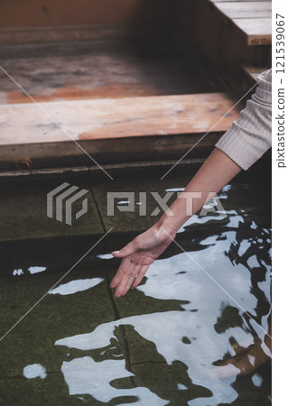 A young woman's hand checking the temperature of the water. (Filming cooperation: Shibata City Film Commission) 121539067