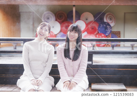 Two young women soaking their feet in a footbath [Filming cooperation: Shibata City Film Commission Council] 121539083