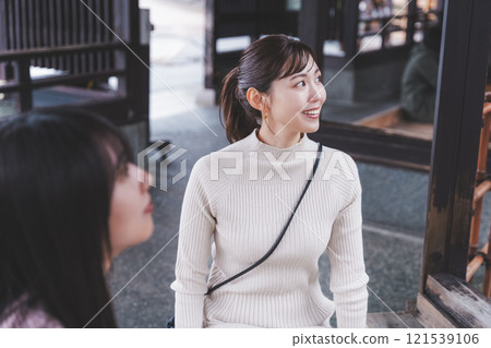 Two young women soaking their feet in a footbath [Filming cooperation: Shibata City Film Commission Council] 121539106