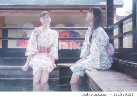 Two young women in yukata soaking their feet in a footbath [Filming cooperation: Shibata City Film Commission Council] 121539121
