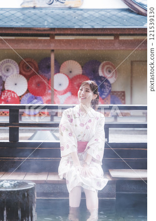A young woman in a yukata soaking her feet in a footbath (Filming cooperation: Shibata City Film Commission Council) 121539130