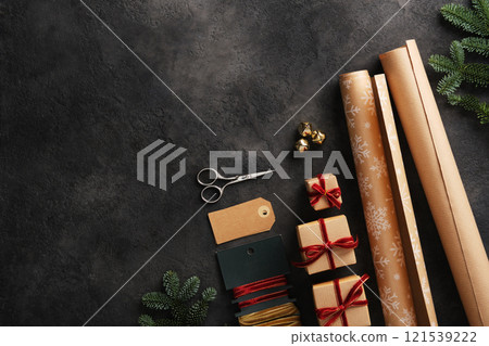 Gift wrapping items, kraft paper rolls, velvet ribbons, scissors and tags on dark background. Space for your text. Gift wrapping items, kraft paper rolls, velvet ribbons, scissors and tags on dark background. Space for your text. 121539222