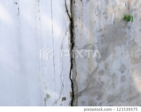 Grey cement walls of the house have dark cracks. Cracked concrete wall background. 121539575