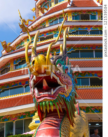 Close-up of colorful dragon decorations on a blue sky background at a Thai temple. 121539584