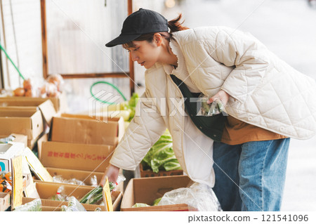 A young female sales clerk arranging products at a traditional fruit and vegetable store. (Photo courtesy of Nuttari Terrace Shopping Arcade) 121541096