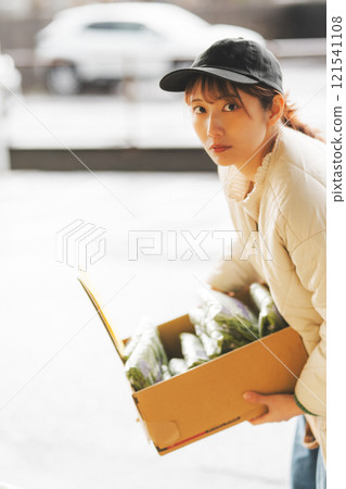 A young female sales clerk arranging products at a traditional fruit and vegetable store. (Photo courtesy of Nuttari Terrace Shopping Arcade) 121541108