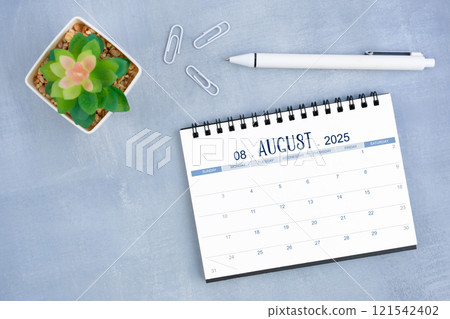 August desk calendar for 2025 year and plant pot with pen on blue cement. August desk calendar for 2025 year and plant pot with pen on blue cement. 121542402