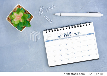 May desk calendar for 2025 year and plant pot with pen on blue cement. May desk calendar for 2025 year and plant pot with pen on blue cement. 121542403