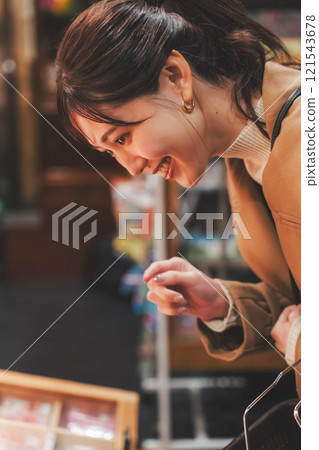 A young woman reminiscing about her past shopping at an old-fashioned candy store [Photo courtesy of Kagata Rice Store, rice and candy store] 121543678