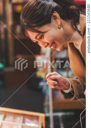 A young woman reminiscing about her past shopping at an old-fashioned candy store [Photo courtesy of Kagata Rice Store, rice and candy store] 121543680