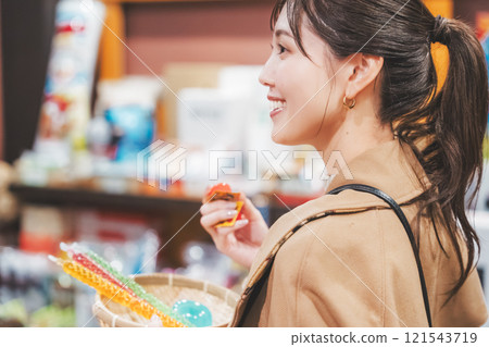 A young woman reminiscing about her past shopping at an old-fashioned candy store [Photo courtesy of Kagata Rice Store, rice and candy store] 121543719