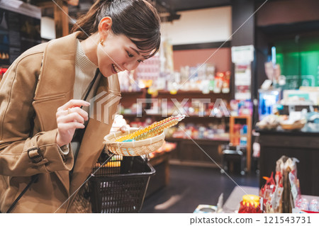 A young woman reminiscing about her past shopping at an old-fashioned candy store [Photo courtesy of Kagata Rice Store, rice and candy store] 121543731