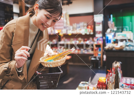 A young woman reminiscing about her past shopping at an old-fashioned candy store [Photo courtesy of Kagata Rice Store, rice and candy store] 121543732