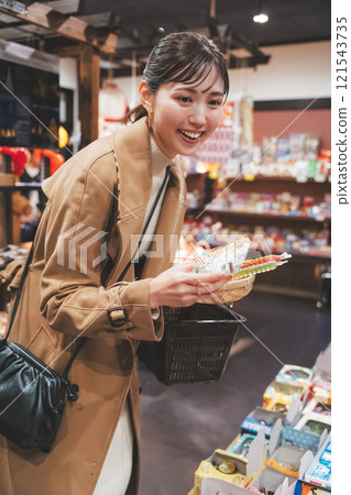 A young woman reminiscing about her past shopping at an old-fashioned candy store [Photo courtesy of Kagata Rice Store, rice and candy store] 121543735