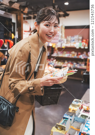 A young woman reminiscing about her past shopping at an old-fashioned candy store [Photo courtesy of Kagata Rice Store, rice and candy store] 121543736