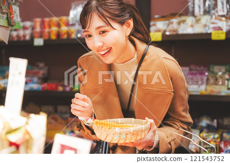 A young woman reminiscing about her past shopping at an old-fashioned candy store [Photo courtesy of Kagata Rice Store, rice and candy store] 121543752