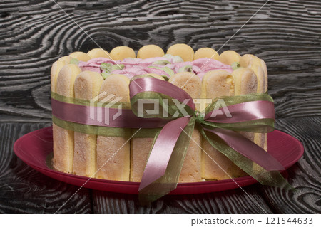Cake with Savoiardi cookies and marshmallow roses. Tied with ribbon. The ribbon is tied into a bow. 121544633