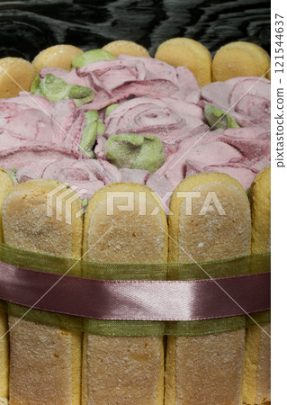 Cake with Savoiardi cookies and marshmallow roses. Tied with ribbon. The ribbon is tied into a bow. 121544637