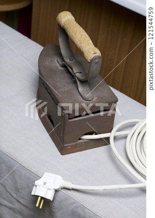 Old iron, heated by hot coals. Located on linen fabric. Visible cord with plug. Collage. 121544759