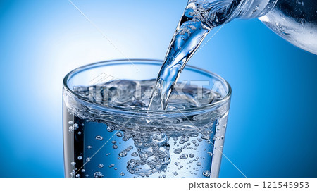 clean water is poured from a bottle into a glass 121545953