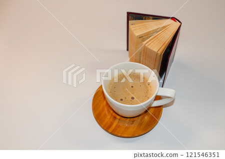 small white cup of cappuccino with vintage book 121546351