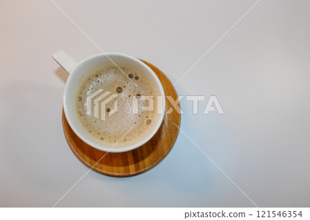 Latte in a beautiful white mug on a wooden plate, delicate foam 121546354