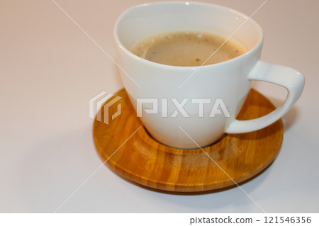 Creamy, frothy coffee in a pristine white mug,resting gently on a wooden coaster 121546356