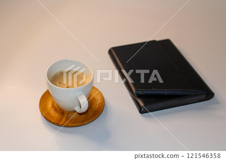 Simple workspace essentials: coffee, a notebook, and a pen. 121546358