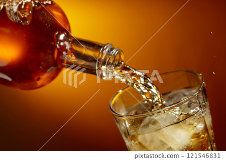 Bottle of whiskey pouring into a glass with ice. 121546831