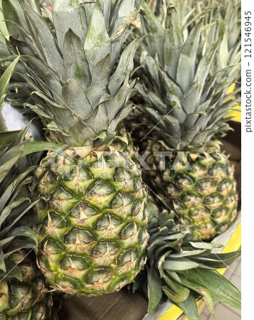 Fresh pineapples displayed at a lively outdoor marketplace in daytime sunlight 121546945