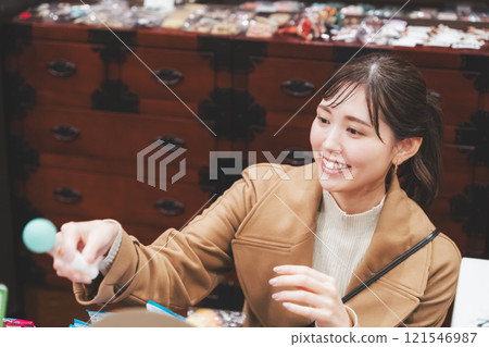 A young woman reminiscing about her past shopping at an old-fashioned candy store [Photo courtesy of Kagata Rice Store, rice and candy store] 121546987