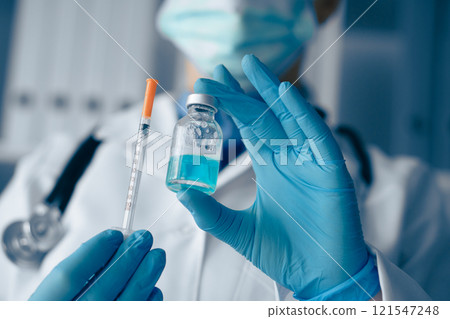 A qualified Medical Professional is preparing a Vaccine with a Syringe and Vial in a sterile environment, ensuring all health protocols are followed for patient safety and immunization efficacy A qualified Medical Professional is preparing a Vaccine with a Syringe and Vial in a sterile environment, ensuring all health protocols are followed for patient safety and immunization efficacy 121547248