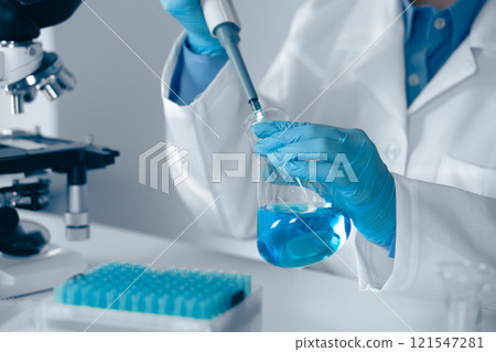 A skilled laboratory technician is engaged in their work utilizing a pipette while wearing blue gloves, showcasing precision and adherence to safety protocols in a scientific research environment A skilled laboratory technician is engaged in their work utilizing a pipette while wearing blue gloves, showcasing precision and adherence to safety protocols in a scientific research environment 121547281