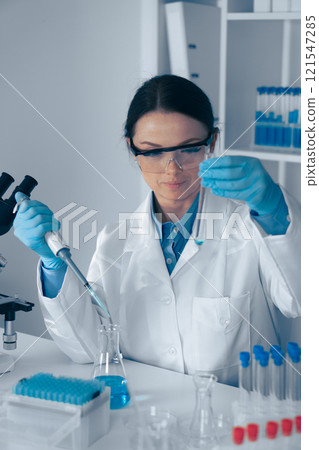A skilled female scientist is conducting a complex experiment with a precision pipette, ensuring accuracy and significantly contributing to advancements and expanding scientific knowledge A skilled female scientist is conducting a complex experiment with a precision pipette, ensuring accuracy and significantly contributing to advancements and expanding scientific knowledge 121547285